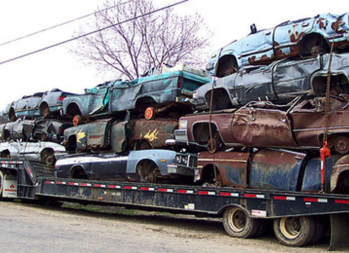 A truck carrying numerous junk cars, demonstrating efficient vehicle transport on the road.