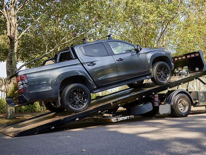 Flatbed tow truck hauling a truck, exemplifying quality car removal services in Brisbane.